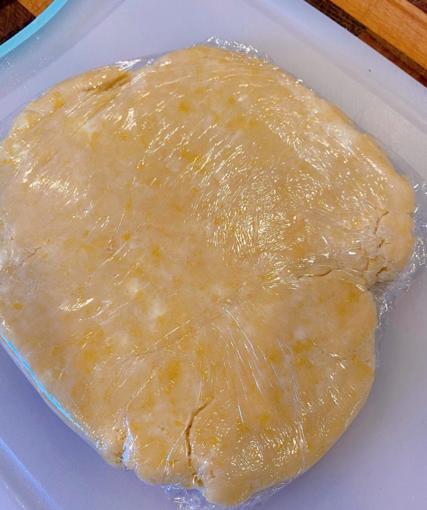 Shortbread crust wrapped in plastic wrap ready to chill.