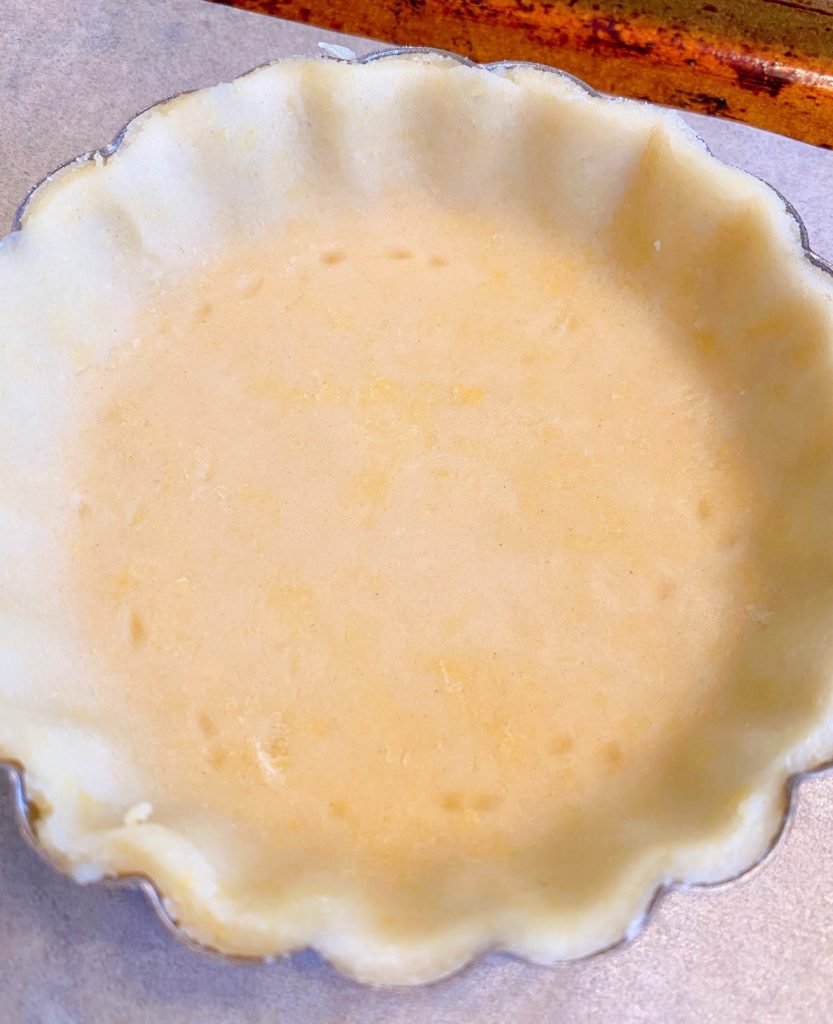 Trimmed shortbread crust in tartlet pan.