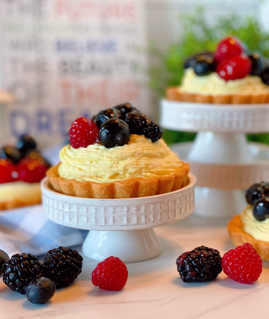 Mini Fruit Tarts on mini cake stands with fresh berries.