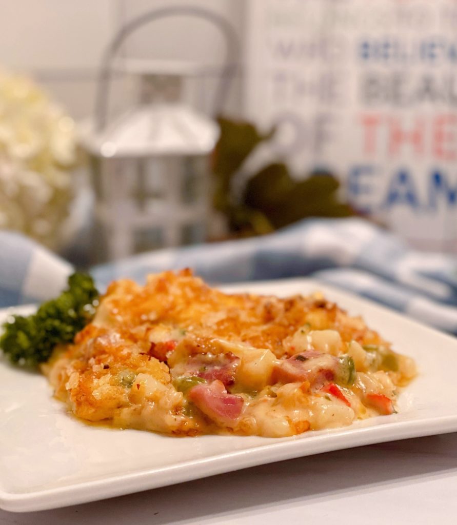 Ham, Broccoli, and Potato casserole on a white dinner plate with a kitchen background.