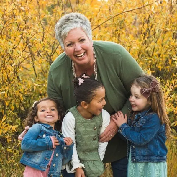 Norine with her granddaughters in a grove of Fall colored trees.