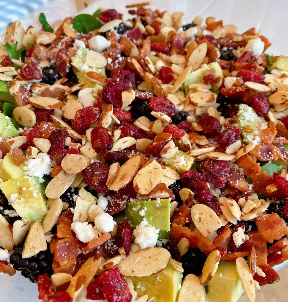 Adding toasted nuts and dried cranberries being adding to the salad.