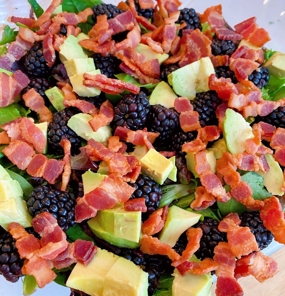 Adding crumbled bacon to salad. 