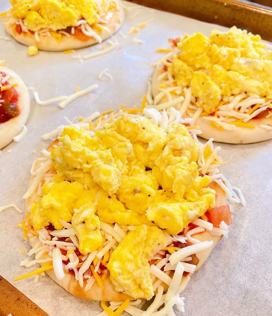 Adding cheese and egg to naan pizza's. 