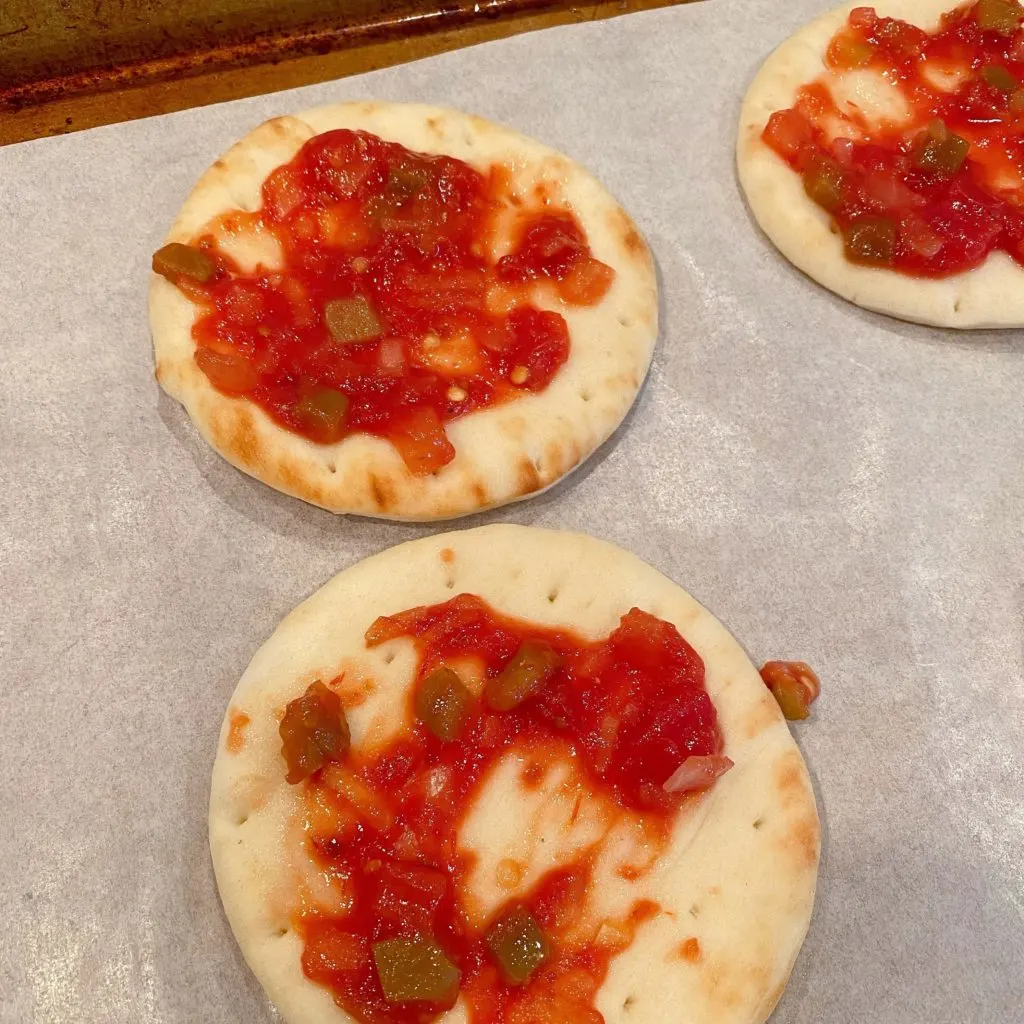 Salsa on top of each slice of naan round on a baking sheet.