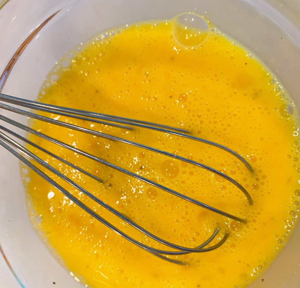 Whisk whisking eggs in a small bowl. 