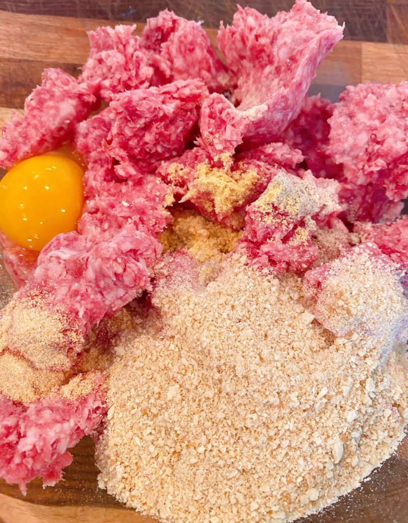 Large glass bowl with ground 50/50, bread crumbs, eggs, seasonins and milk to make meatballs.