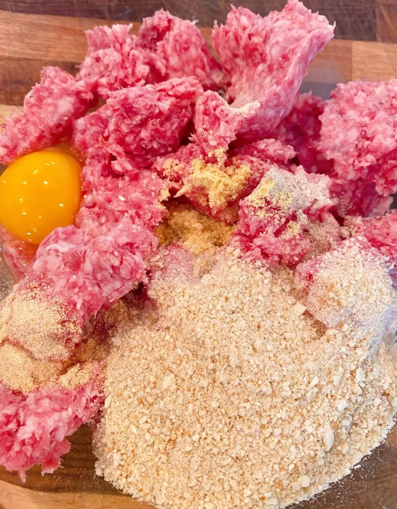 Large glass bowl with ground 50/50, bread crumbs, eggs, seasonins and milk to make meatballs.