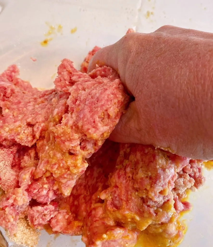 Mixing meatball ingredients with hands to combine all the ingredients.
