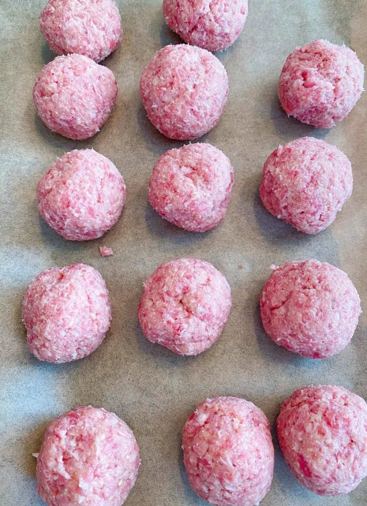 Meatballs on parchment lined baking sheet. 