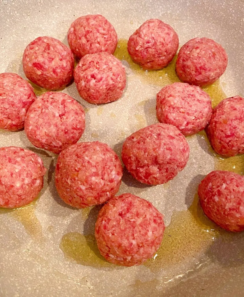 Meatballs in large pot browning.