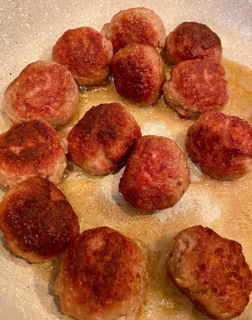 Meatballs cooking in large skillet. 