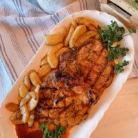 Grilled Honey Garlic Pork Chops with fried cinnamon apples on a white platter.