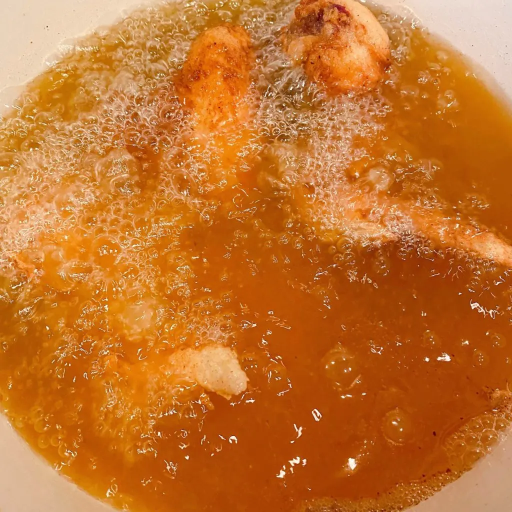 Frying Chicken in hot oil in dutch oven on stove top.