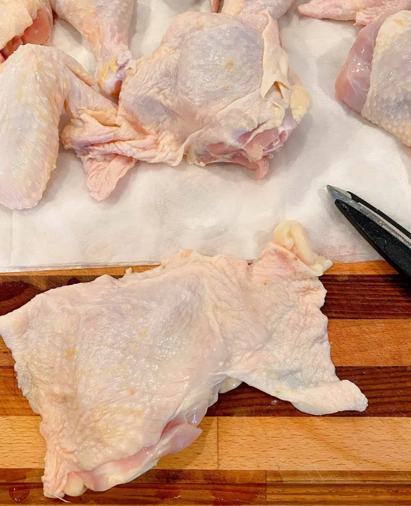 Chicken on cutting board laid out to show extra skin on pieces.