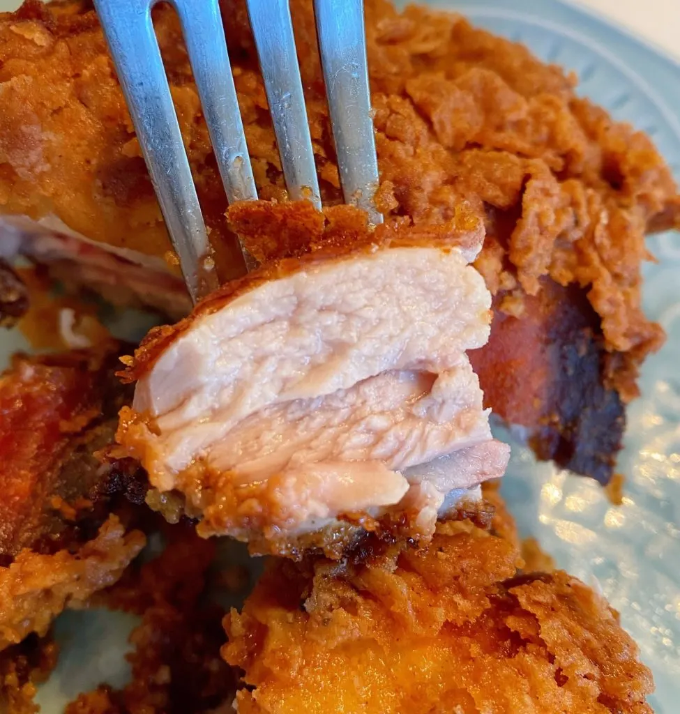 Fork with a piece of juicy chicken on it.