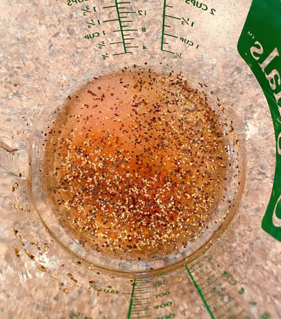 Red wine vinegar, salt, pepper, and sugar for mayo dressing in measuring cup.