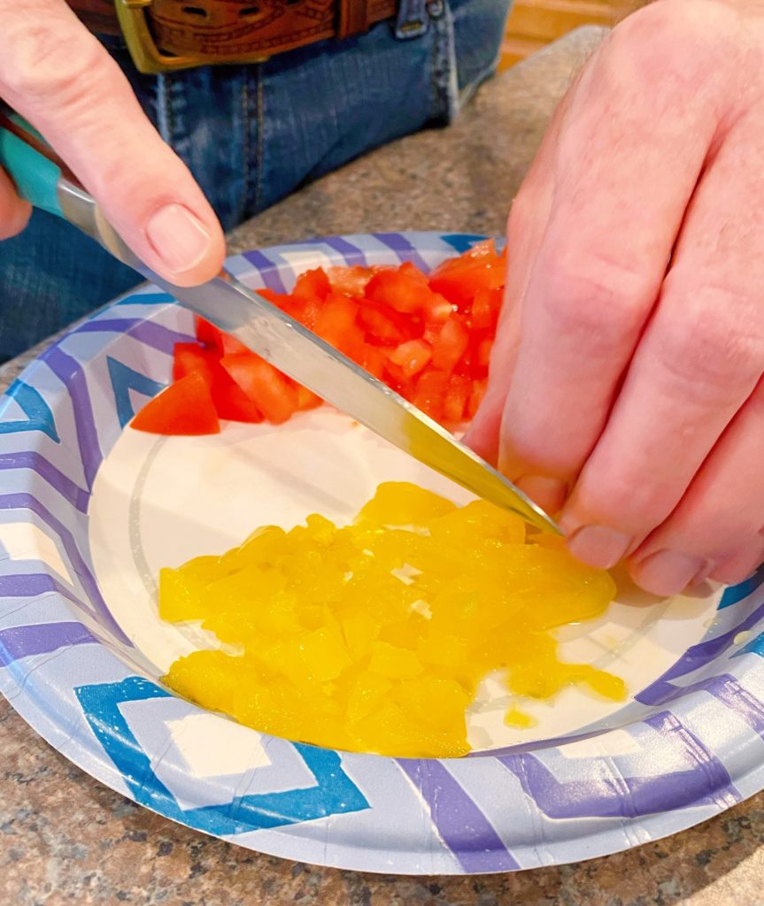 dicing banana peppers and tomatoes on a paper plate.