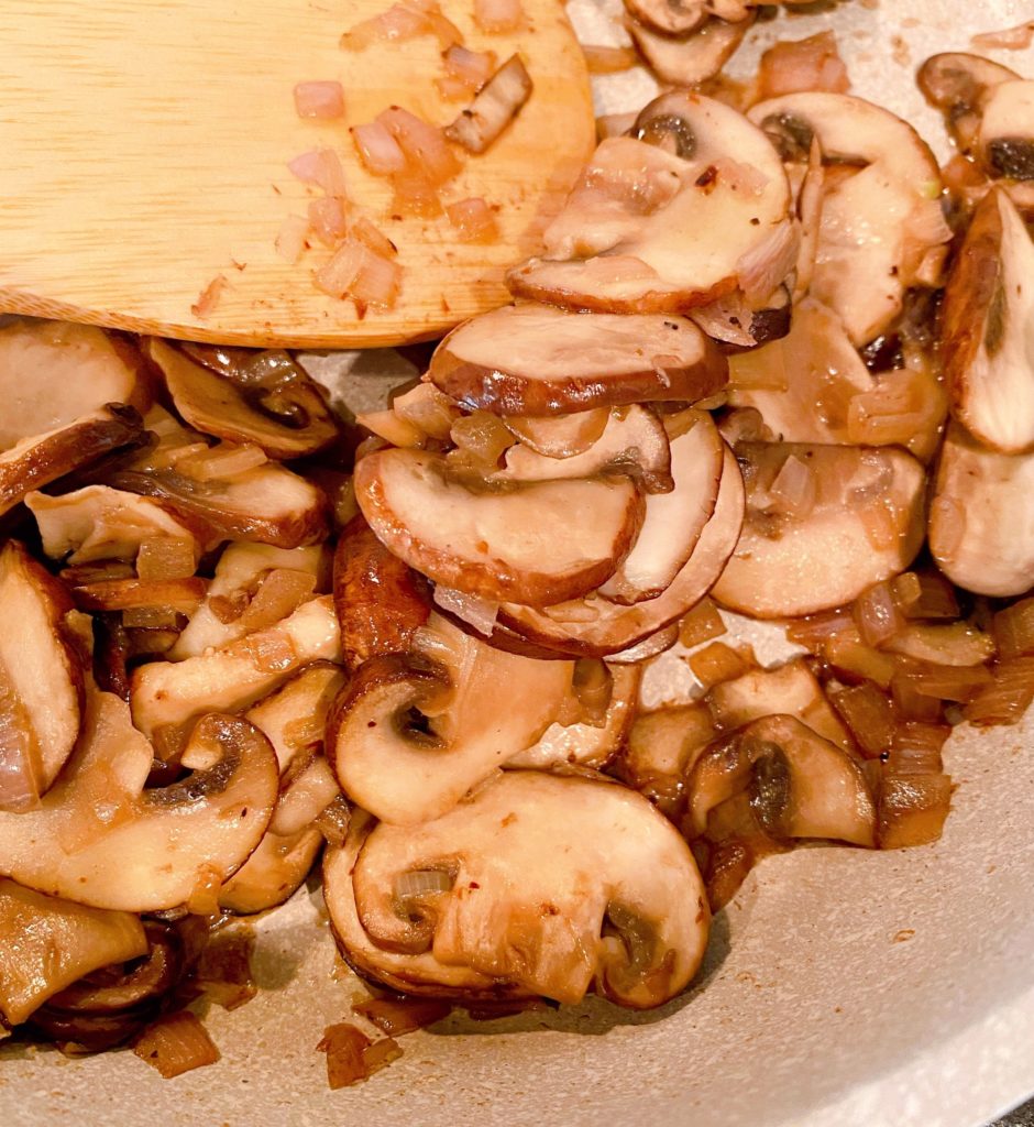 Sauteing mushrooms and shallots in skillet.
