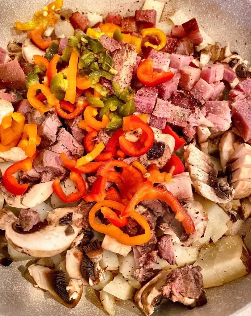 Skillet ingredients, peppers, potatoes, meats, etc. in a large skillet over medium heat.