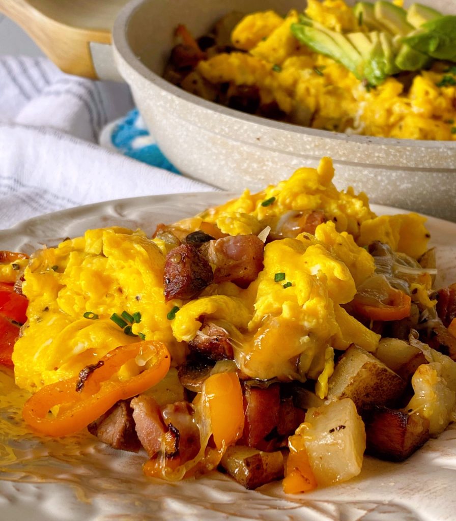 Skillet Breakfast on a serving plate with a skillet full in the background.