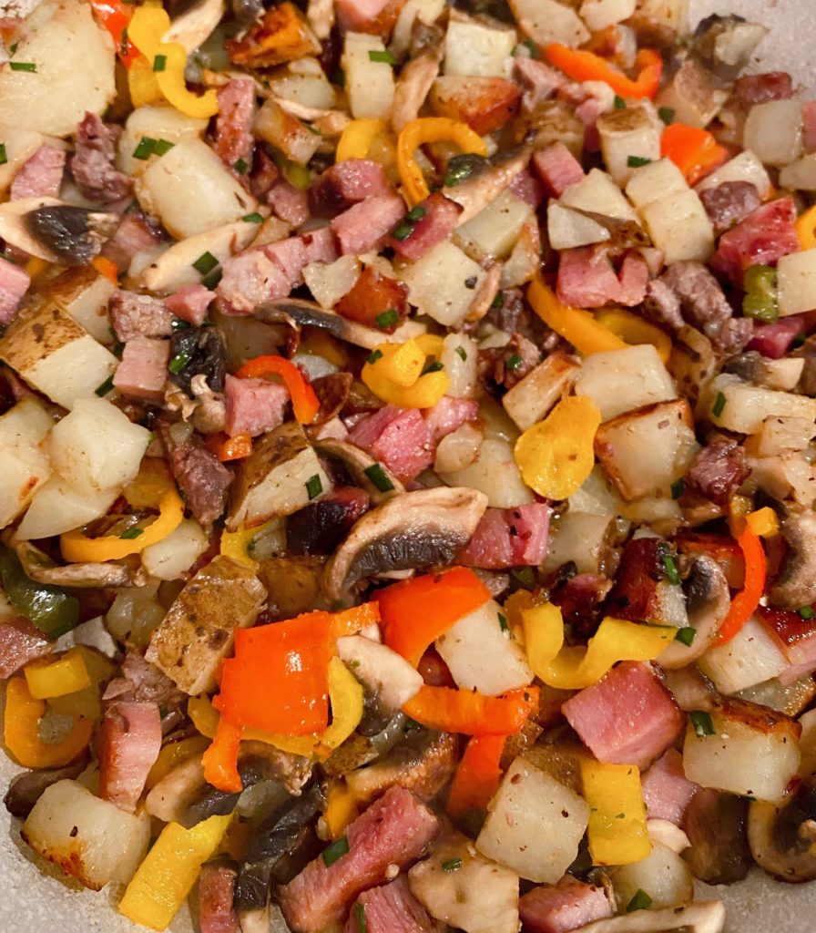 Cooked Potatoes, meat, and veggies in skillet. 