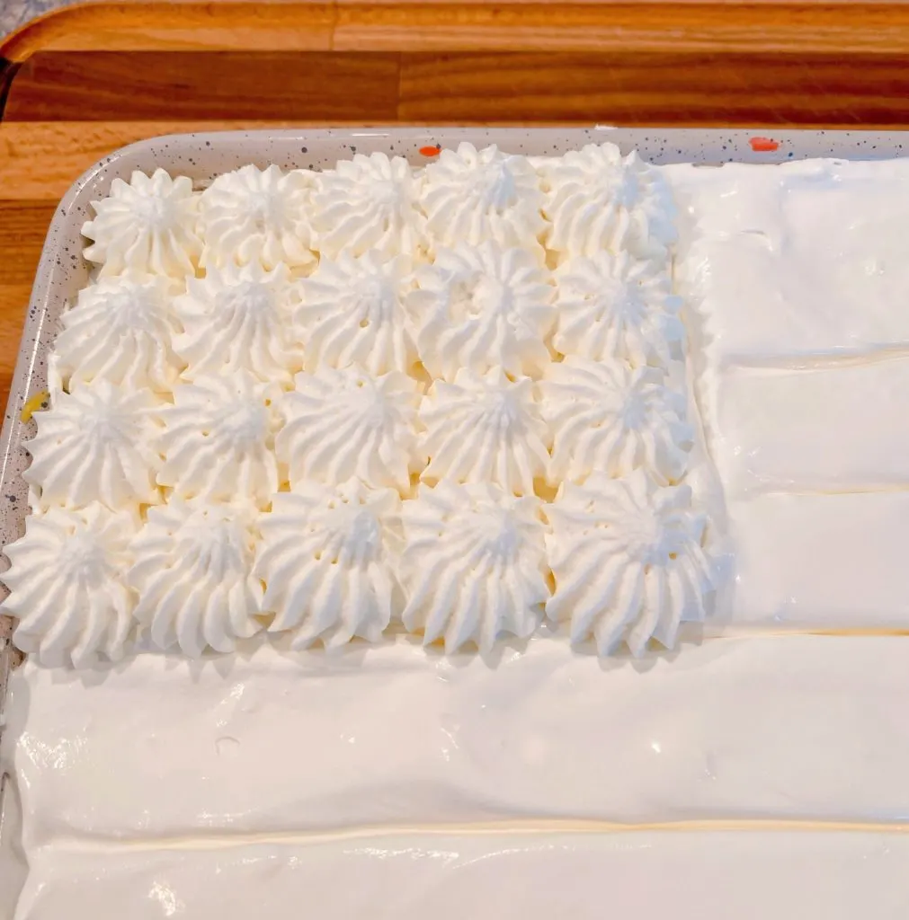 Cake with lines drawn on the top and whip cream stars.