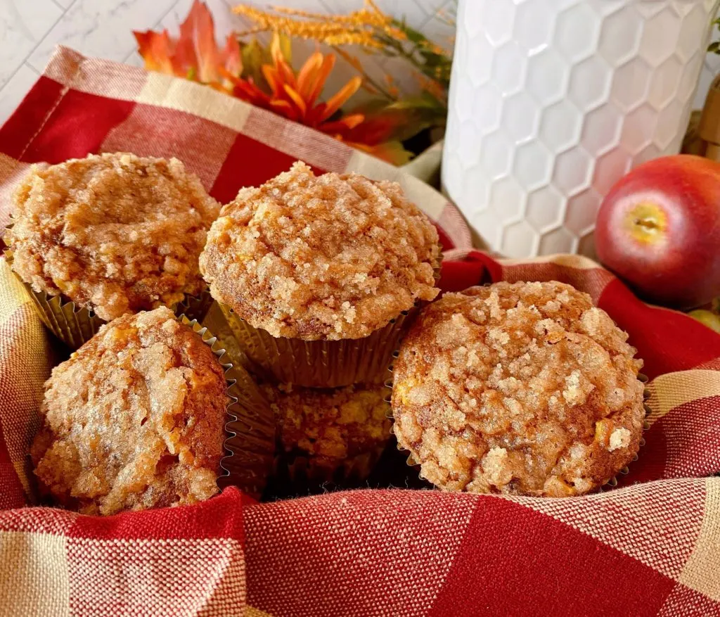 Pumpkin Apple Streusel Muffins on a plaid napkin in a basket.