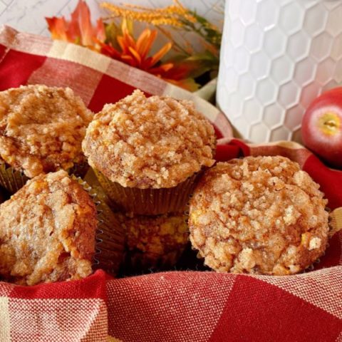 Pumpkin Apple Streusel Muffins on a plaid napkin in a basket.