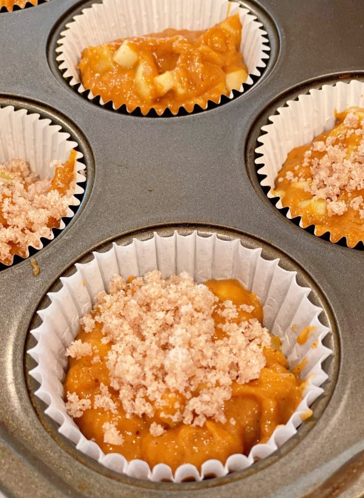 Muffins in tin with crumb topping waiting to be baked.