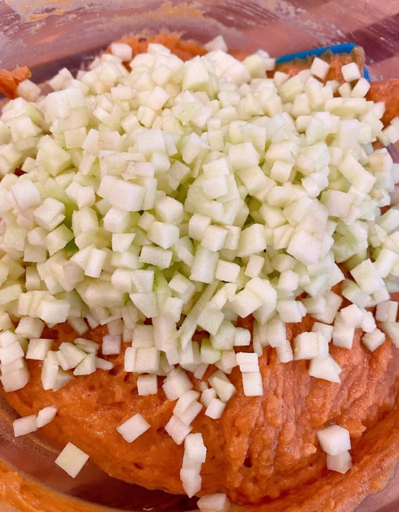 Adding chopped apples to pumpkin batter.