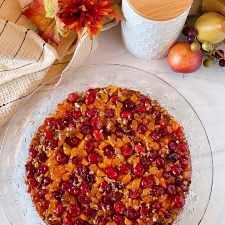 Overhead photo of Cranberry Upside down cake on a crystal cake plate on a white counter top.