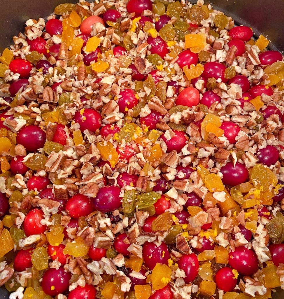 Adding chopped nuts to cake top with cranberries.