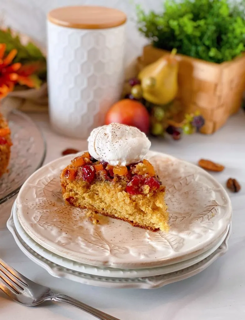 Cake with dollop of whipped cream on  a stack of plates.