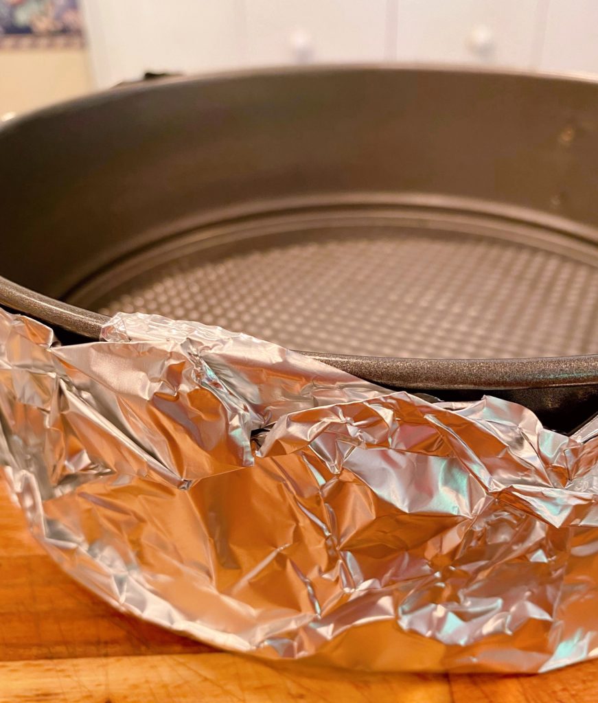 Springform pan wrapped in aluminum foil for baking.