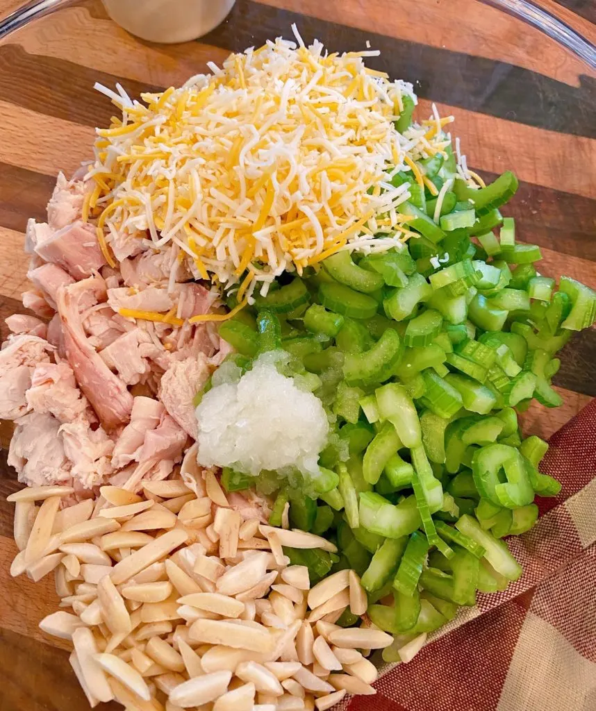 Adding ingredients to chicken salad recipe in mixing bowl.