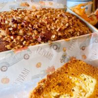 Pumpkin Cream Cheese Pecan Streusel Bread in a loaf pan with a slice near it.