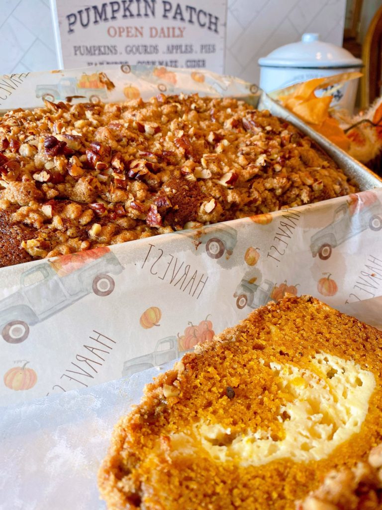 Pumpkin Cream Cheese Pecan Streusel Bread in a loaf pan with a slice near it.
