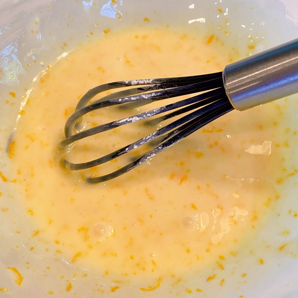 Orange Glaze in mixing bowl with small wire whisk.