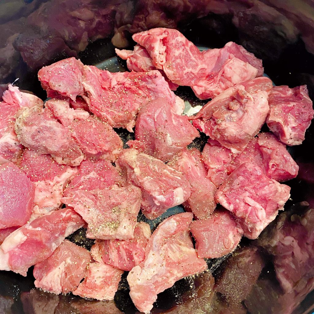 2 pounds of stew beef with salt and pepper in the bottom of a slow cooker.