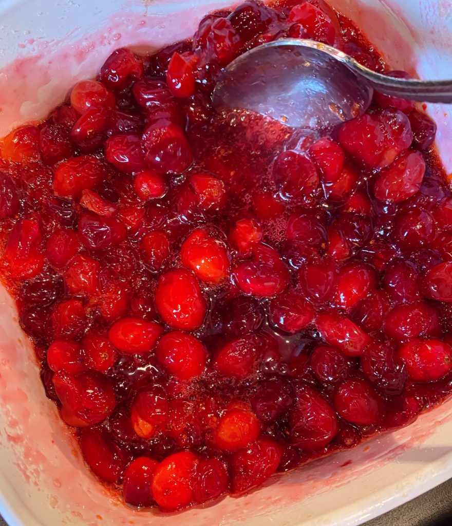 Baked Berries in a casserole dish with a spoon stirring them.