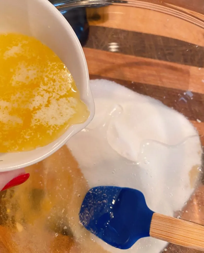 Sugar, corn syrup, vanilla in a large mixing bowl with melted butter being added.