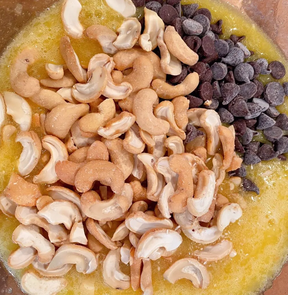 Adding Cashews and semi-sweet chocolate chips to pie filling.