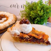 Slice of Chocolate Cashew Pie on dessert plate with whipped cream garnish and chocolate covered cashew.