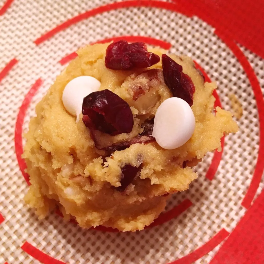 Adding cranberries and chocolate chips on top of each cookie.