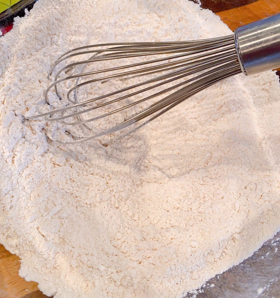Combining dry ingredients in a large bowl with a whisk.