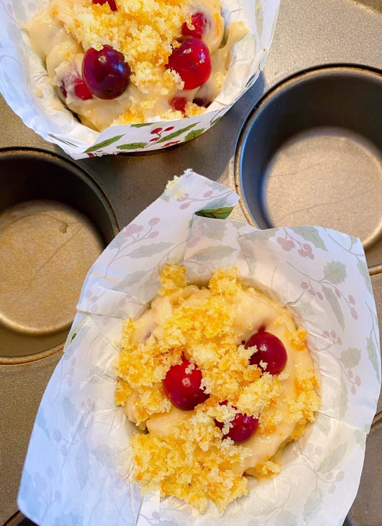 Muffin in muffin tin sprinkled with orange sugar zest. Ready to bake.