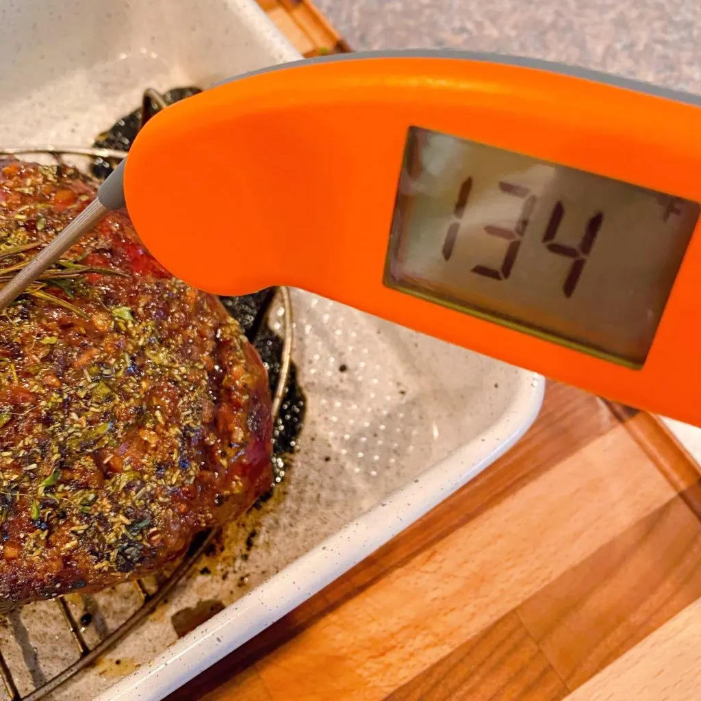 Meat thermometer inserted into roast checking the temperature.