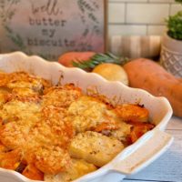 Rosemary Triple-potato gratin in a white baking dish with ingredients behind.