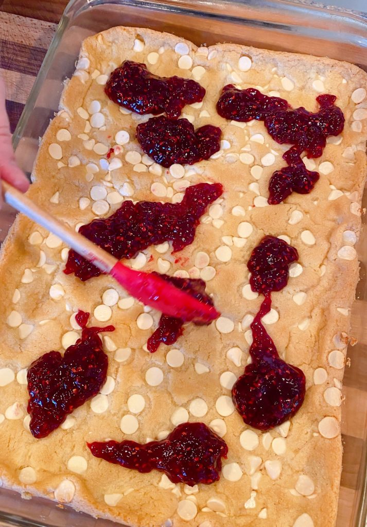 Spreading raspberry jam over white chocolate crust.